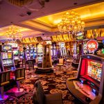 Interior view of a brightly lit casino with multiple slot machines and tables