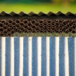 A close-up of a fence made of corrugated metal and chicken wire.